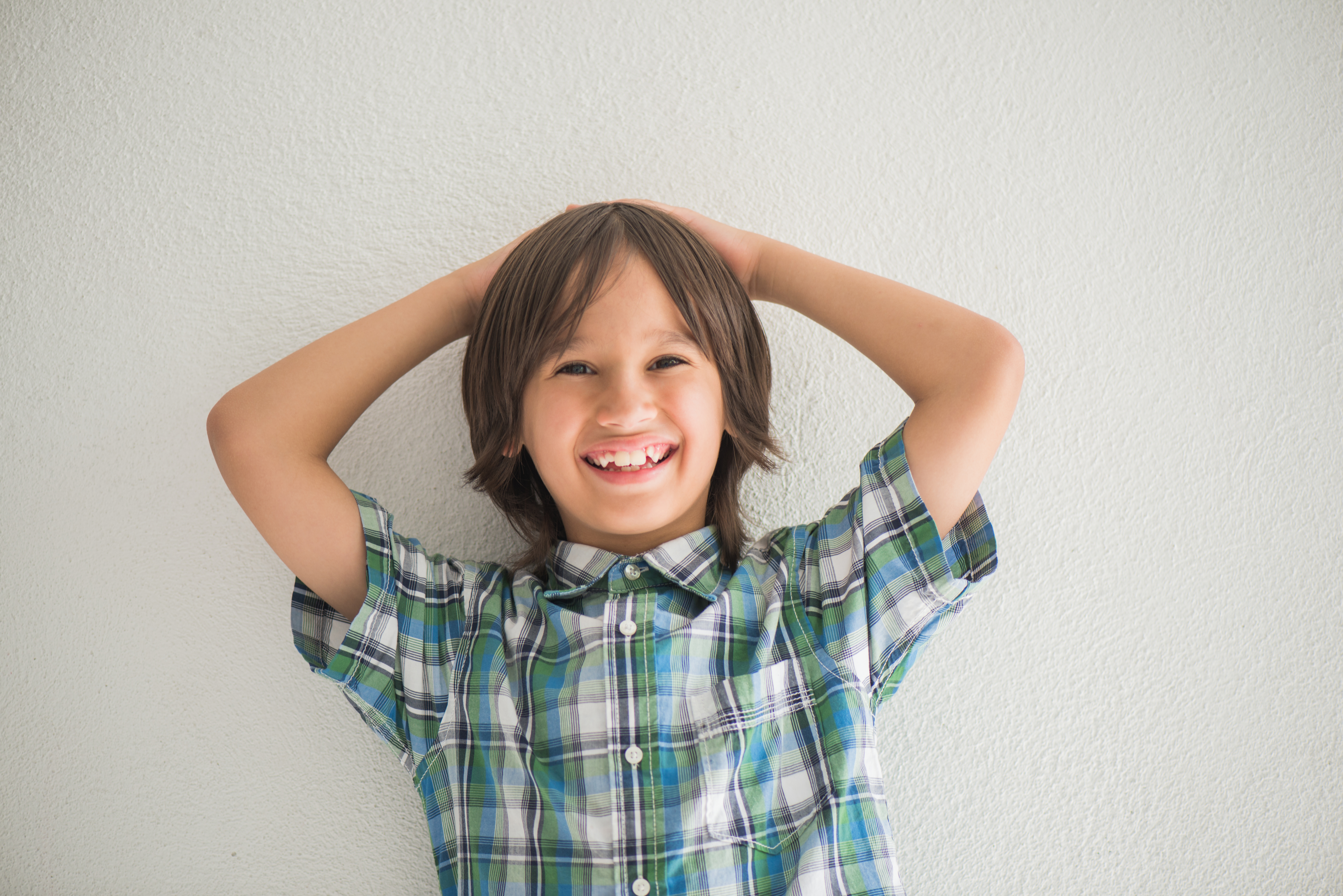 Smiling boy posing in front of a wall